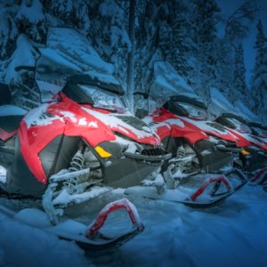 Polar night landscape with row of red snowmobiles